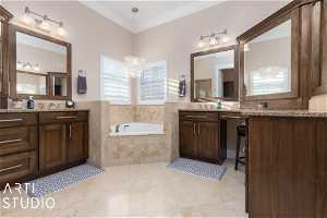 Primary bathroom featuring vanity, tile floors, tiled tub, and crown molding