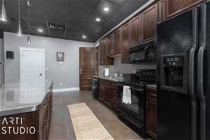Theater room kitchen featuring black appliances, a paneled ceiling, dark brown cabinets, and sink