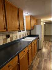 Kitchen with dishwasher, sink, a textured ceiling, backsplash, and dark hardwood / wood-style floors