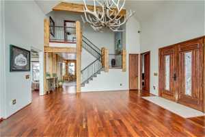 Foyer entrance featuring dark hardwood / wood-style floors, high vaulted ceiling, and a notable chandelier