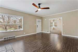 Spare room with dark hardwood / wood-style flooring, ceiling fan, and ornamental molding