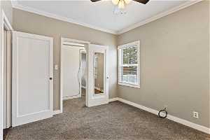 Unfurnished bedroom with ceiling fan, carpet, and crown molding