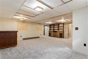 Basement featuring carpet, baseboard heating, and a paneled ceiling