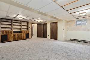 Basement featuring carpet floors, a paneled ceiling, and baseboard heating