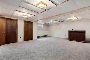 Basement featuring a paneled ceiling, carpet, and a baseboard radiator