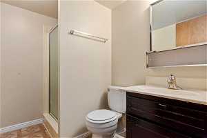 Bathroom featuring an enclosed shower, large vanity, and toilet