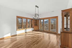 Spare room featuring an inviting chandelier, a wealth of natural light, washer / clothes dryer, and light hardwood / wood-style flooring