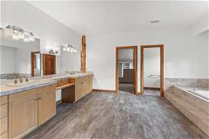 Bathroom with tiled bath, hardwood / wood-style flooring, and dual bowl vanity