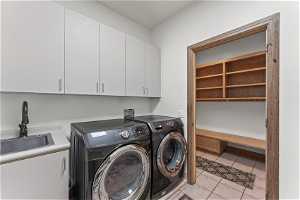 Laundry room featuring light tile floors, sink, washer hookup, cabinets, and washing machine and clothes dryer