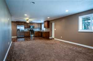 Kitchen featuring sink, a textured ceiling, appliances with stainless steel finishes, dark colored carpet, and ceiling fan