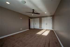 Unfurnished bedroom featuring ceiling fan, a textured ceiling, carpet, and two closets