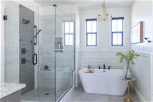 Bathroom featuring separate shower and tub, tile floors, tile walls, and a notable chandelier