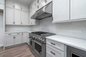 Kitchen with white cabinets, beverage cooler, light hardwood / wood-style floors, and range with two ovens