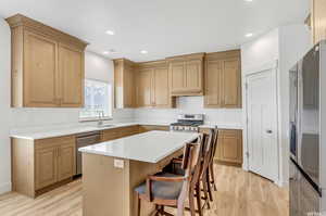 Kitchen with a kitchen bar, light wood-type flooring, a center island, and stainless steel appliances