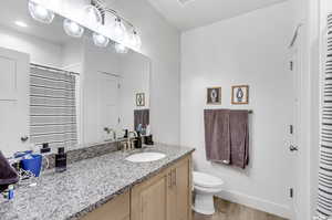 Bathroom with toilet, wood-type flooring, and vanity