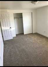 Master bedroom with dark colored carpet and a closet