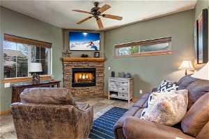 Tiled living room with ceiling fan and a fireplace