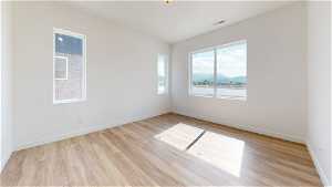 Empty room featuring a wealth of natural light, a water view, and light hardwood / wood-style floors
