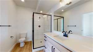 Bathroom featuring toilet, a shower with door, hardwood / wood-style flooring, and vanity