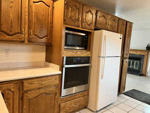 Kitchen featuring a high end fireplace, light colored carpet, stainless steel appliances, and backsplash