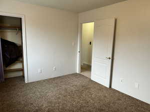 Unfurnished bedroom with a  closet, and dark colored carpet