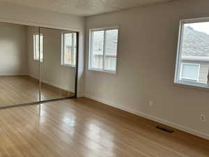 Unfurnished bedroom with a closet, a textured ceiling, and light hardwood / wood-style floors