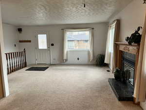 Living room with light colored carpet, a textured ceiling, and a tiled fireplace