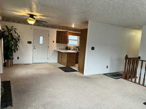 Interior space featuring light carpet, ceiling fan, and a textured ceiling