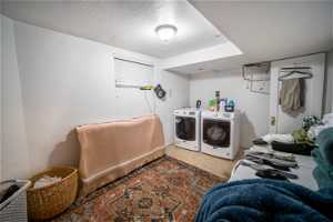 Laundry area featuring a textured ceiling, separate washer and dryer, and light tile floors