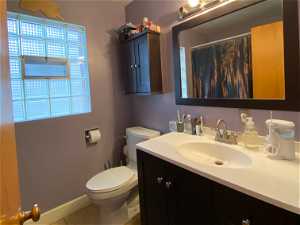 Bathroom featuring toilet, tile floors, oversized vanity, tile shower