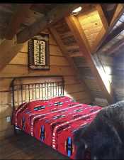 Bunk House: Bedroom featuring lofted ceiling with beams, wood walls, and hardwood / wood-style flooring