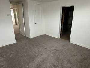 Unfurnished bedroom featuring a closet and dark colored carpet