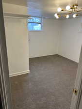 Basement with a chandelier and dark colored carpet