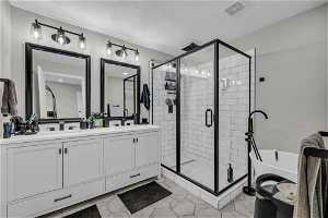 Bathroom featuring double sink vanity, an enclosed shower, and tile flooring