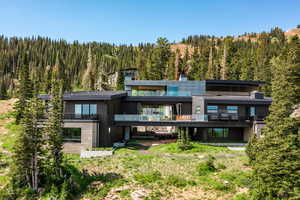 Rear view of property featuring a view of trees and a balcony
