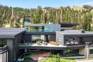Rear view of house with a forest view, a chimney, a balcony, metal roof, and a standing seam roof