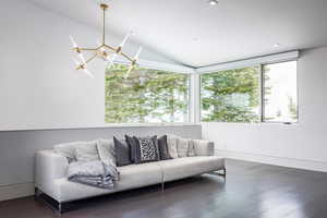 Living room with dark wood-style floors, vaulted ceiling, and a chandelier