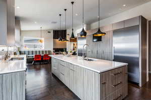 Kitchen with modern cabinets, built in refrigerator, a sink, a large island with sink, and light countertops