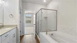 Bathroom with wood-type flooring, vanity with extensive cabinet space, separate shower and tub, and ceiling fan