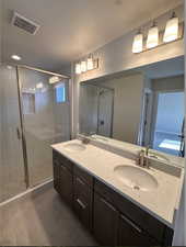 Primary bathroom with tile patterned flooring, walk in shower, and vanity