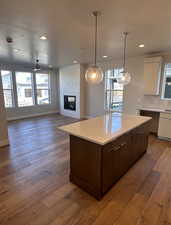 Kitchen featuring a large fireplace, white cabinets, ceiling fan, and hardwood / wood-style floors