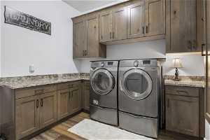 Main floor laundry room with dark hardwood / wood-style floors, cabinets, granite countertops and separate washer and dryer