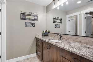 Lower level bathroom featuring tile floors, vanity, and backsplash, granite countertops