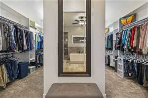 Owners suite Spacious closet featuring light carpet and ceiling fan