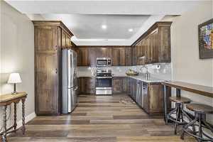 Kitchen featuring light granite countertops, appliances with stainless steel finishes, hardwood / wood-style flooring, backsplash, and sink