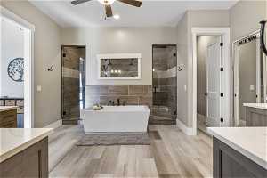 Owners Bathroom with vanity, granite countertops, plus walk in shower, and ceiling fan