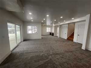 Empty room with a wealth of natural light and dark colored carpet