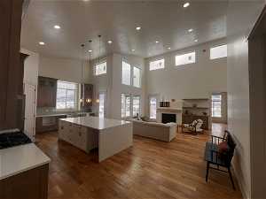 Kitchen featuring hanging light fixtures, a high ceiling, a center island, and a healthy amount of sunlight