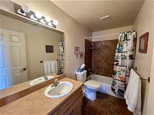 Guest bathroom with shower / tub combo with curtain, oversized vanity, toilet, and tile flooring