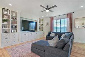 Living room featuring built in features, light hardwood / wood-style floors, and ceiling fan